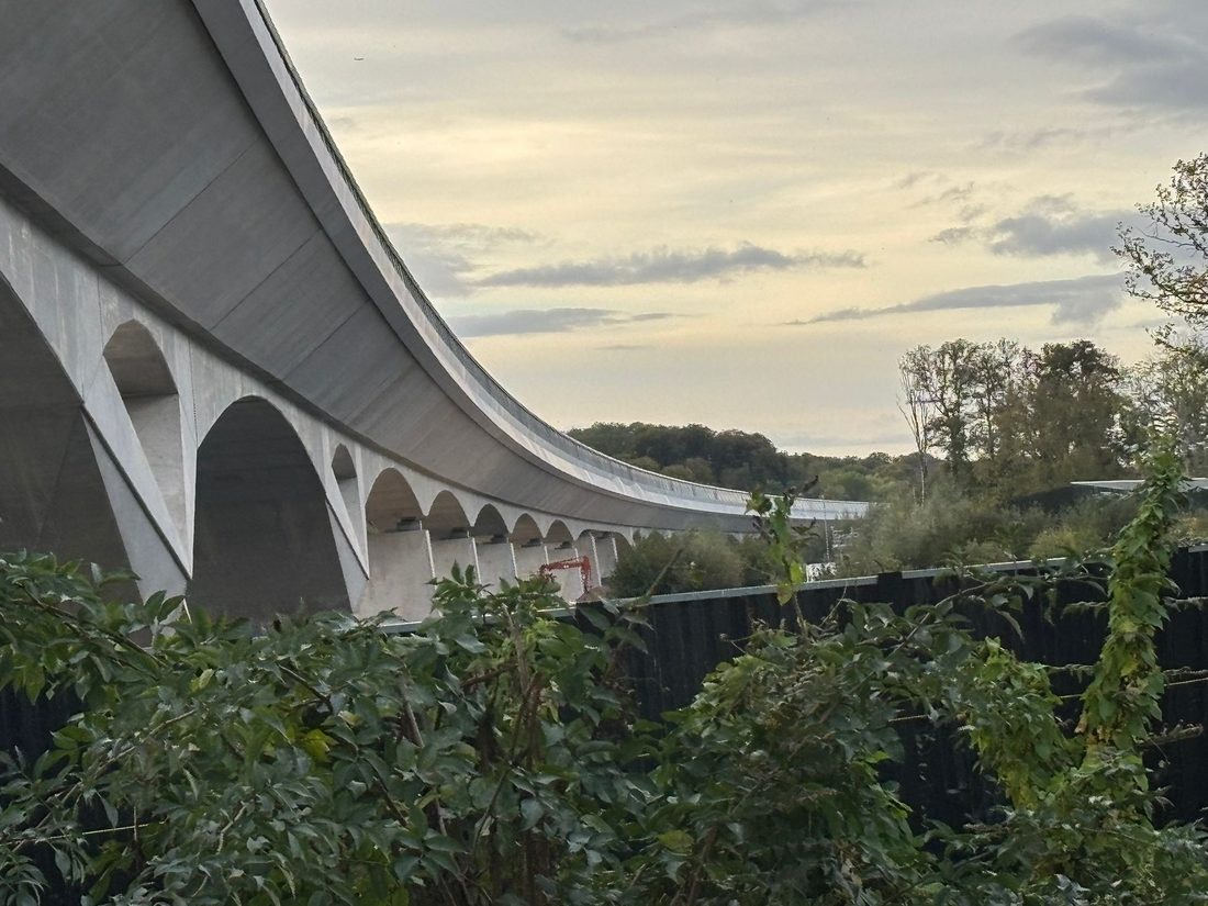 A large concrete viaduct seen from the canal bank